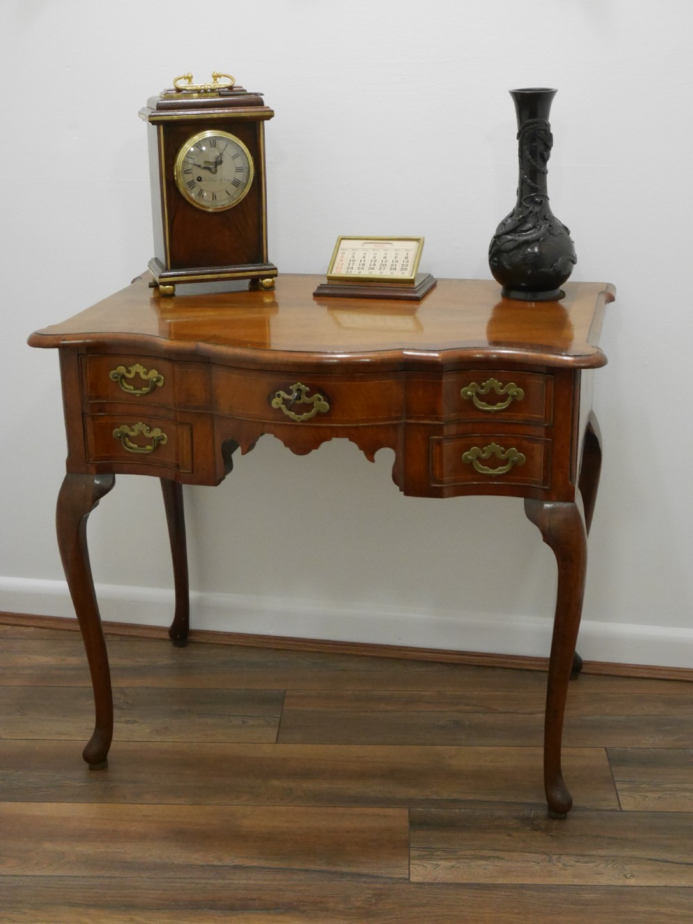 A late eighteenth-century walnut lowboy table featuring cabriole legs, brass handles, a shaped front apron, and five drawers. View II