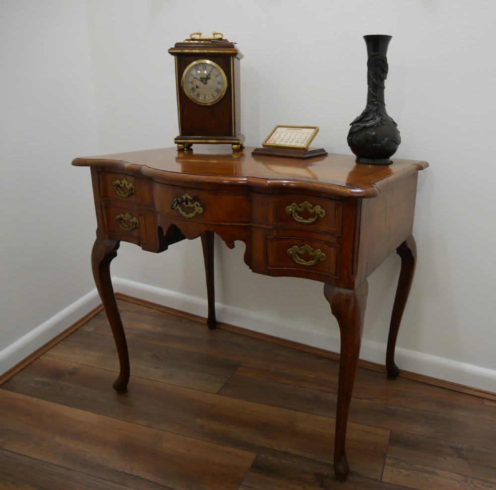 A late eighteenth-century walnut lowboy table featuring cabriole legs, brass handles, a shaped front apron, and five drawers. View III