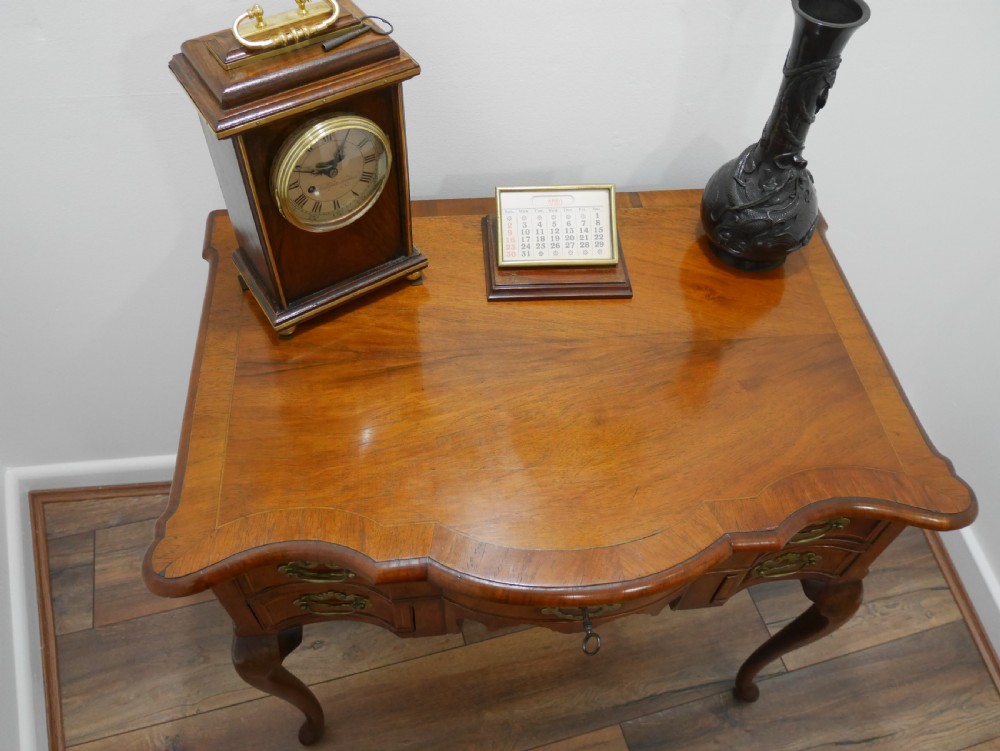 A late eighteenth-century walnut lowboy table featuring cabriole legs, brass handles, a shaped front apron, and five drawers. View IV