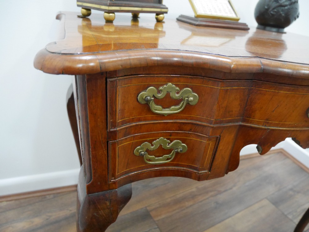 A late eighteenth-century walnut lowboy table featuring cabriole legs, brass handles, a shaped front apron, and five drawers. View V