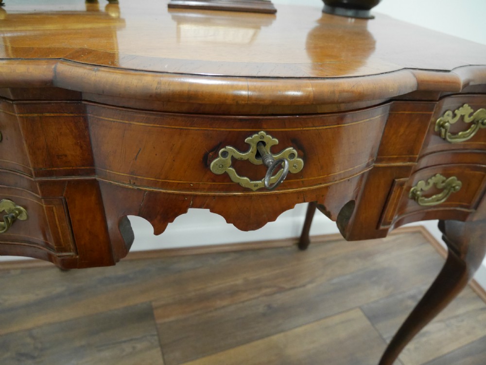 A late eighteenth-century walnut lowboy table featuring cabriole legs, brass handles, a shaped front apron, and five drawers. View VI