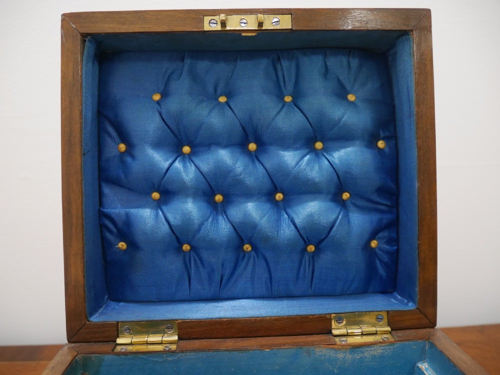 An open Victorian walnut dressing box featuring a blue button-tufted lining, three cut glass scent bottles, and brass hardware. View V