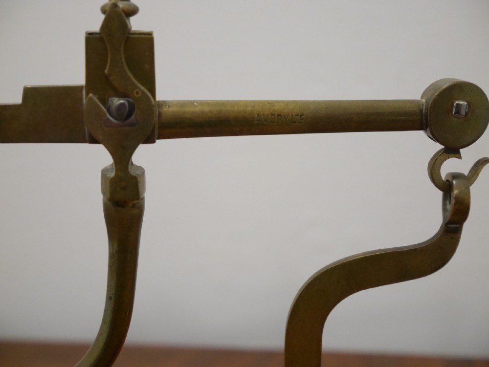 An antique brass balance scale featuring a graduated measurement beam, sliding weight, and single suspended pan mounted on a mahogany base. View III