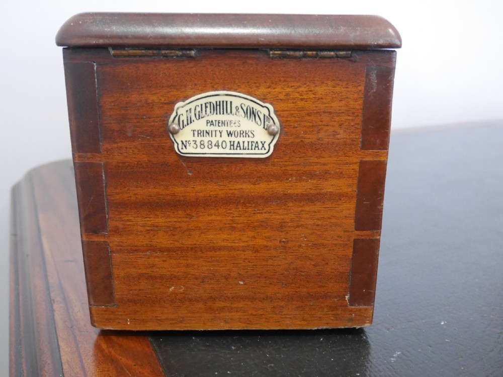 An open mahogany Gledhill patent cash till showing internal mechanical brass parts, a paper roll mechanism, and a printed paper instruction label on the underside of the lid. View IV