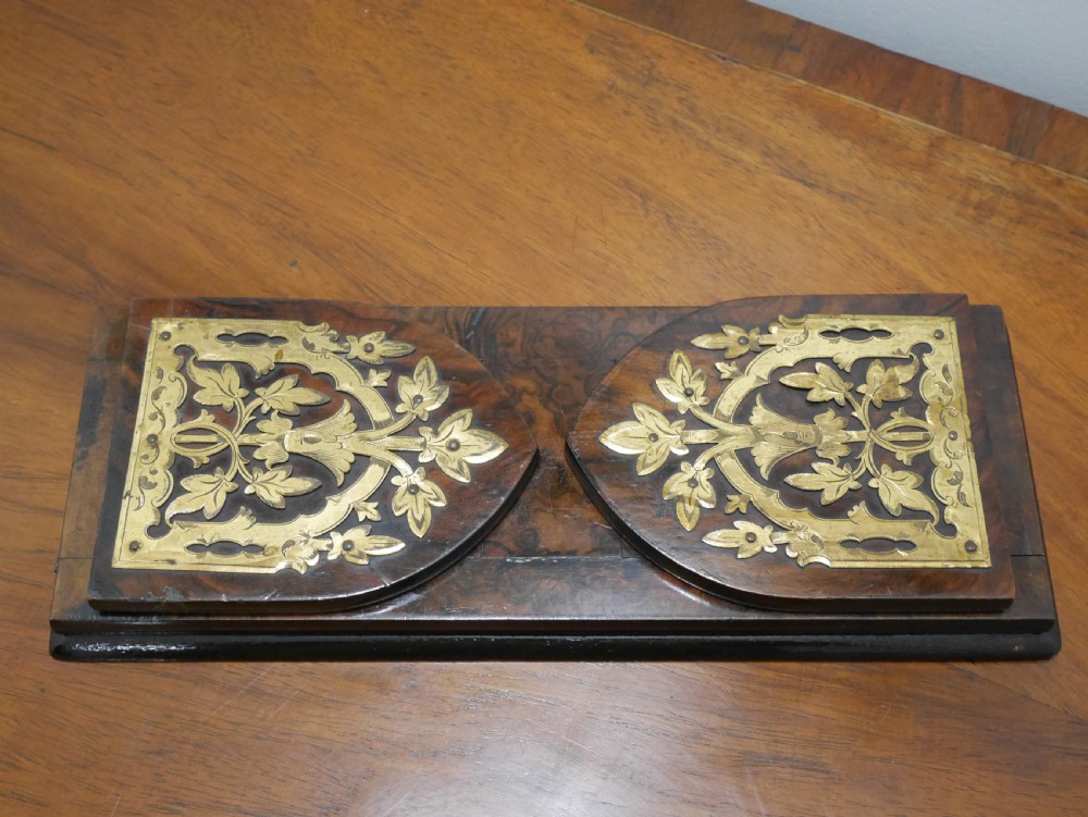 A nineteenth-century walnut book slide shown folded flat, decorated with pierced brass foliate strapwork on the hinged end panels.