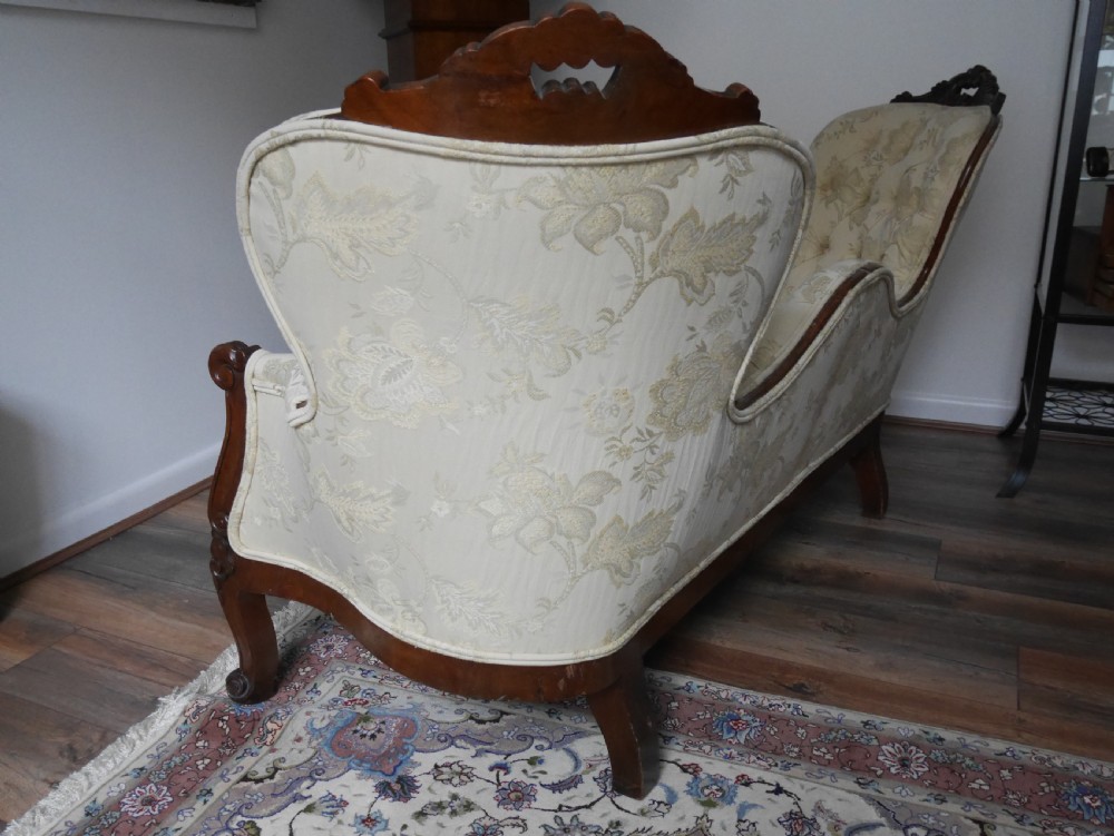 A Victorian double end settee with a carved mahogany frame, cabriole legs, and button-tufted cream damask upholstery. View III