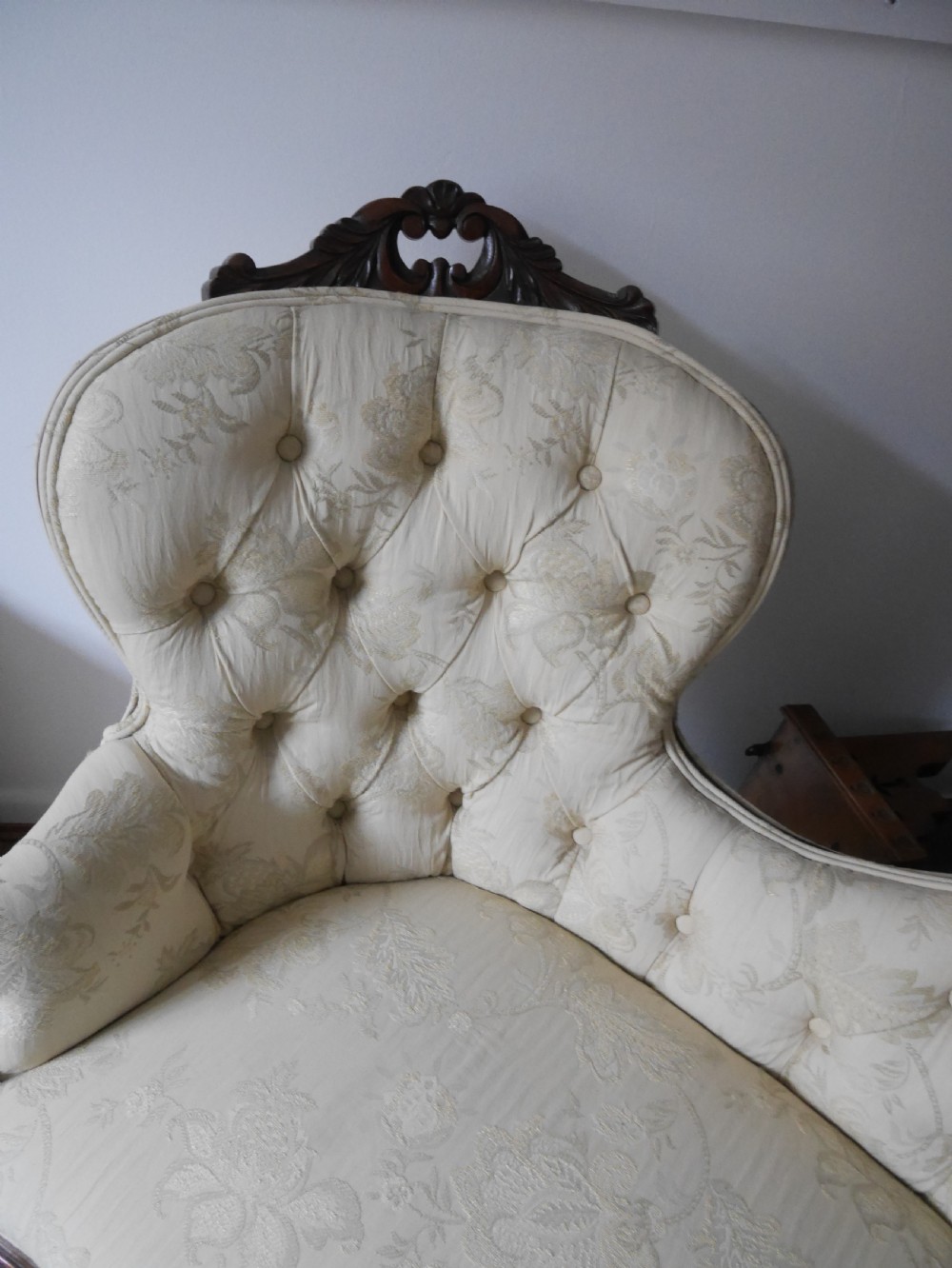 A Victorian double end settee with a carved mahogany frame, cabriole legs, and button-tufted cream damask upholstery. View V