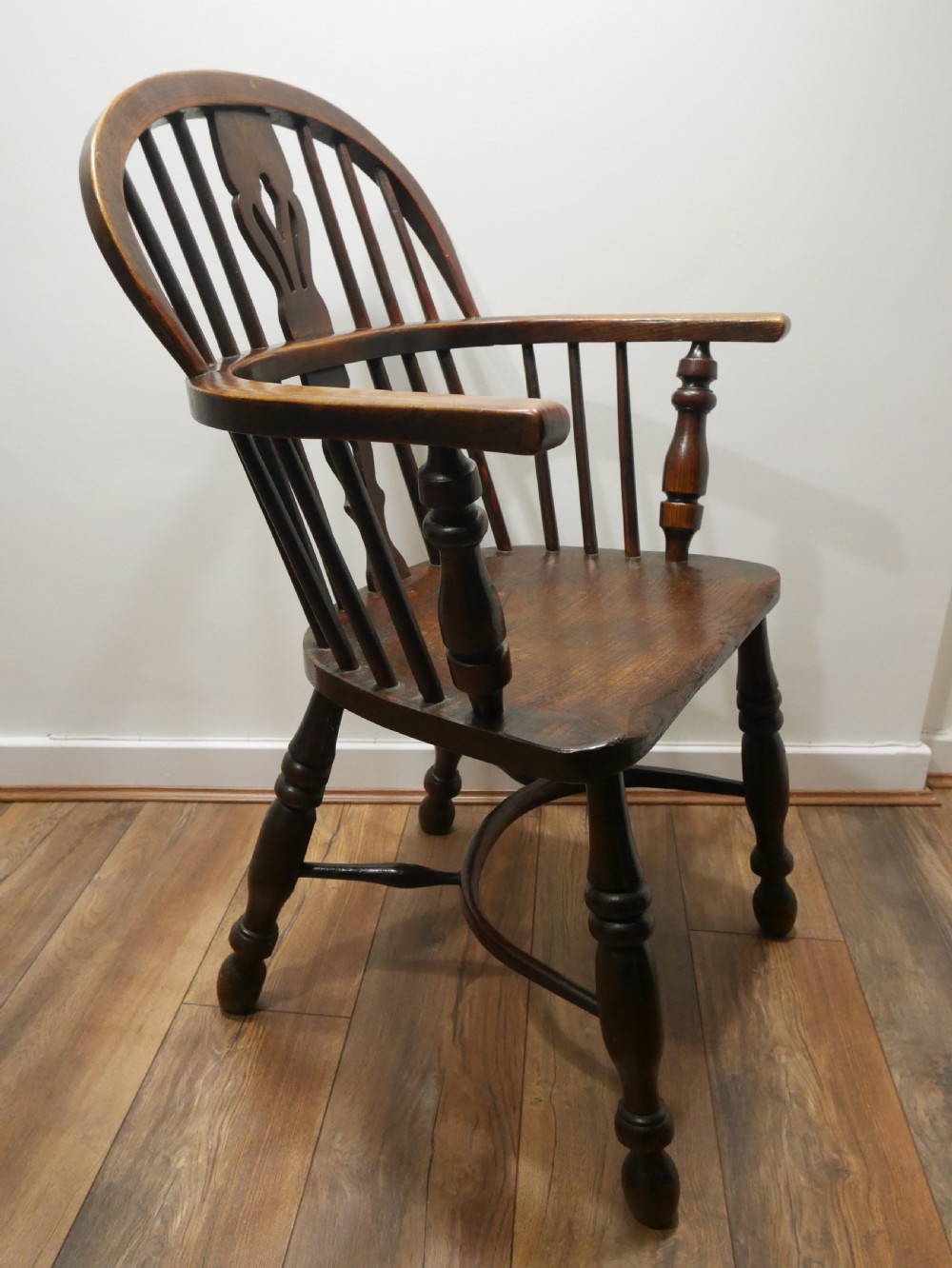 A dark brown antique wooden Windsor armchair featuring a hoop back with a central pierced splat, spindled backrest, shaped seat, turned legs, and a stretcher base. View II