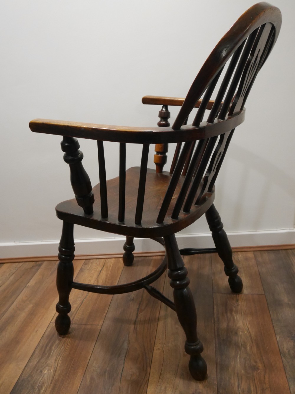 A dark brown antique wooden Windsor armchair featuring a hoop back with a central pierced splat, spindled backrest, shaped seat, turned legs, and a stretcher base. View IV