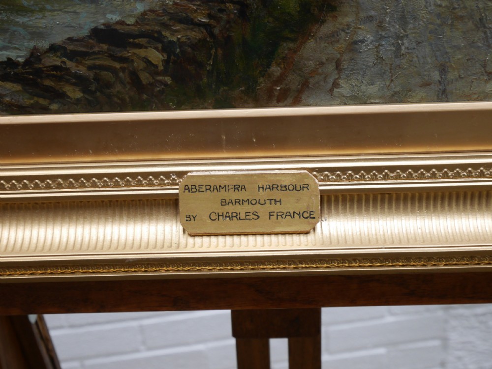 An oil painting on canvas depicting Aberamffra Harbour with moored boats and a shepherd on a stone road, set in a gilded frame. View V
