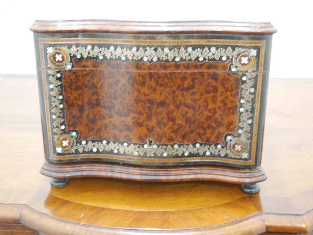 A French serpentine-front thuya wood box featuring foliate marquetry inlay, mother-of-pearl accents, a brass keyhole, and small turned feet.