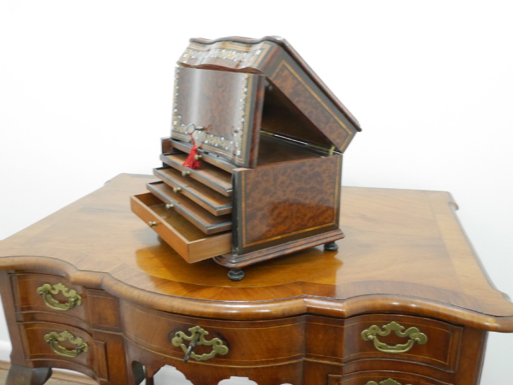 A French serpentine-front thuya wood box featuring foliate marquetry inlay, mother-of-pearl accents, a brass keyhole, and small turned feet. View IV