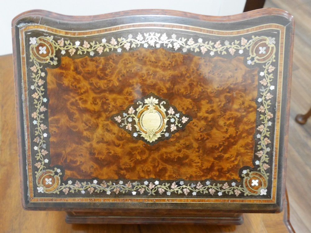 A French serpentine-front thuya wood box featuring foliate marquetry inlay, mother-of-pearl accents, a brass keyhole, and small turned feet. View VII