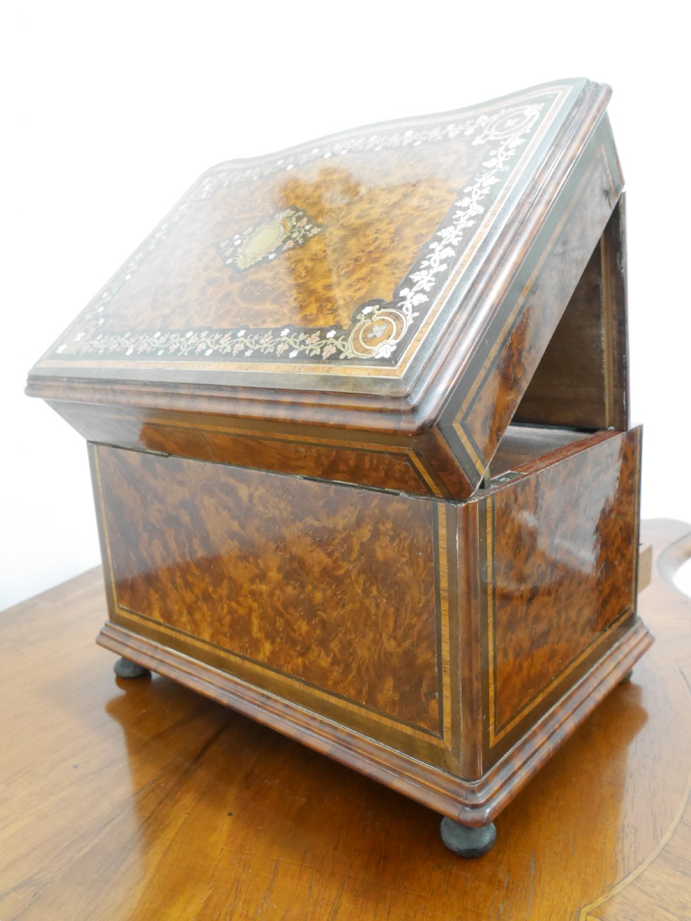 A French serpentine-front thuya wood box featuring foliate marquetry inlay, mother-of-pearl accents, a brass keyhole, and small turned feet. View VIII
