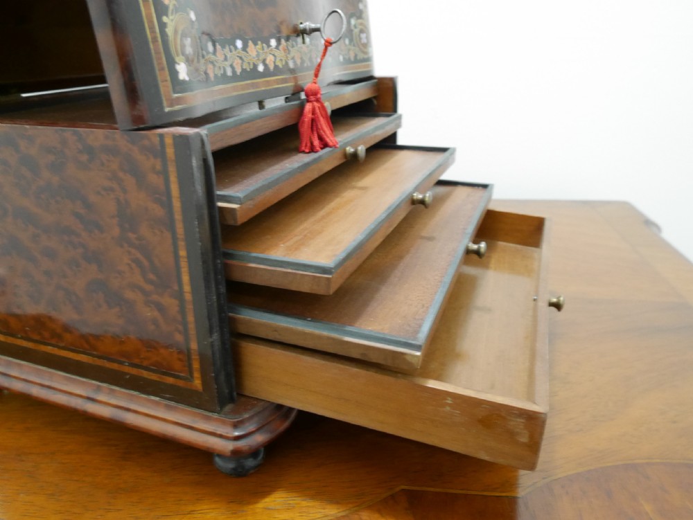 A French serpentine-front thuya wood box featuring foliate marquetry inlay, mother-of-pearl accents, a brass keyhole, and small turned feet. View IX