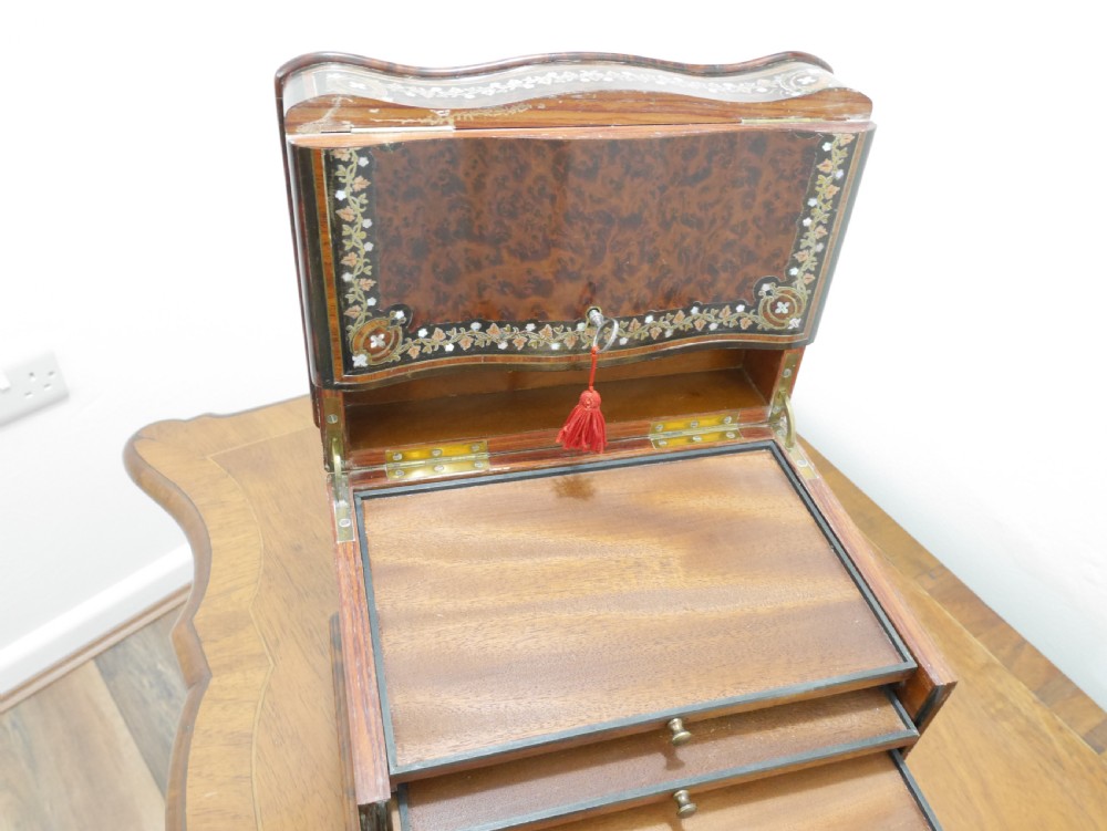 A French serpentine-front thuya wood box featuring foliate marquetry inlay, mother-of-pearl accents, a brass keyhole, and small turned feet. View X