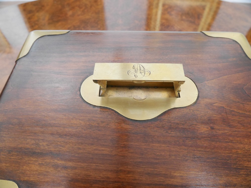 An open antique brass-bound wooden dressing box featuring a red velvet interior, integrated lid mirror, and fitted glass bottles with metal caps. View IV