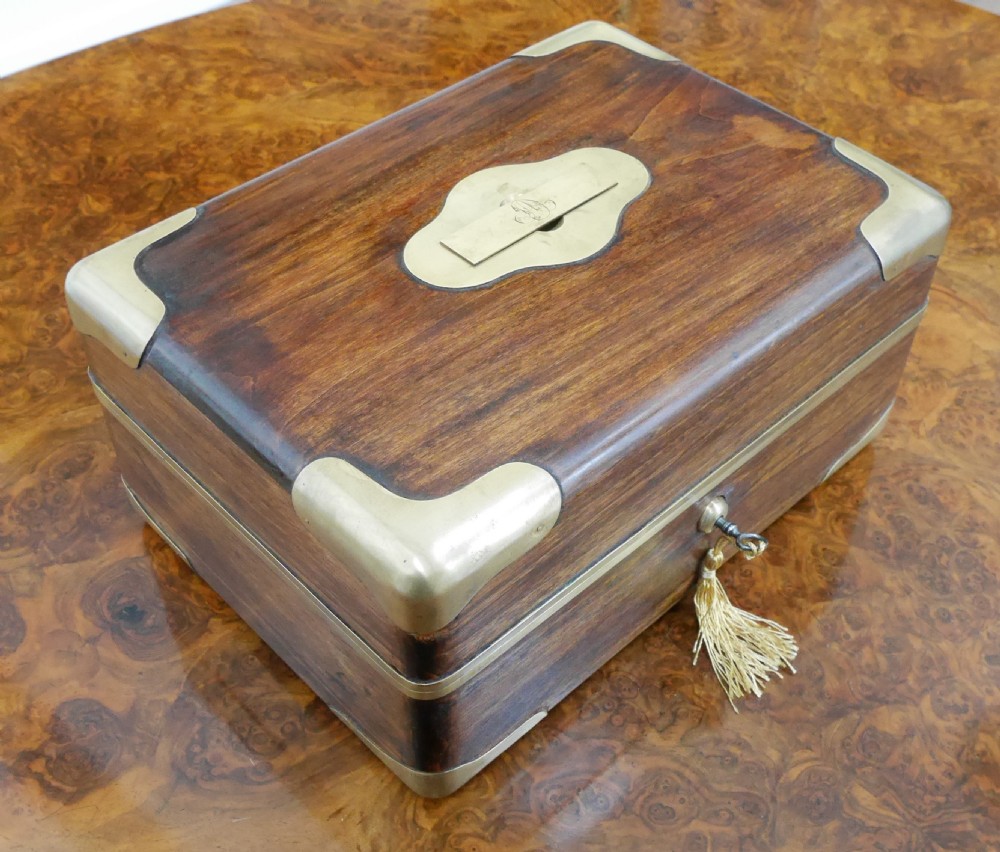 An open antique brass-bound wooden dressing box featuring a red velvet interior, integrated lid mirror, and fitted glass bottles with metal caps. View V