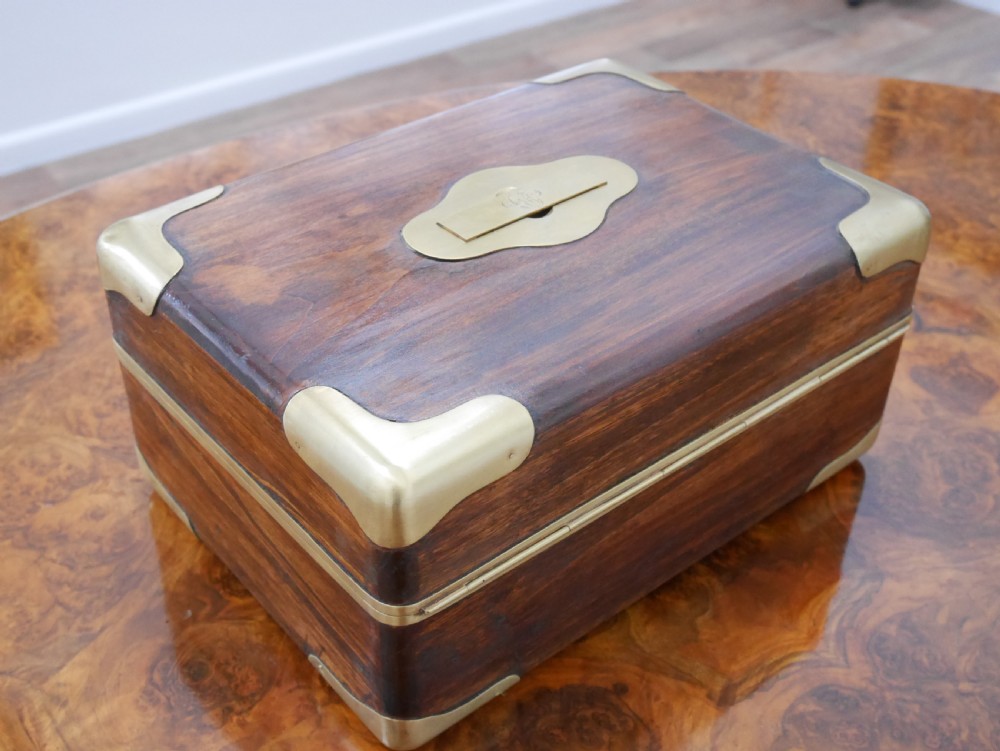 An open antique brass-bound wooden dressing box featuring a red velvet interior, integrated lid mirror, and fitted glass bottles with metal caps. View VI