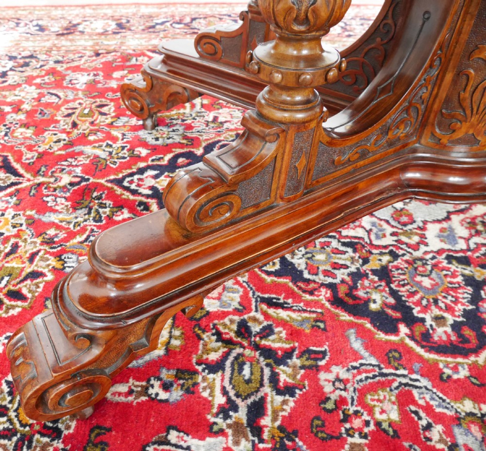 An oval Victorian burr walnut tilt-top loo table featuring figured timber grain and a carved central pedestal base with four scroll feet. View VII