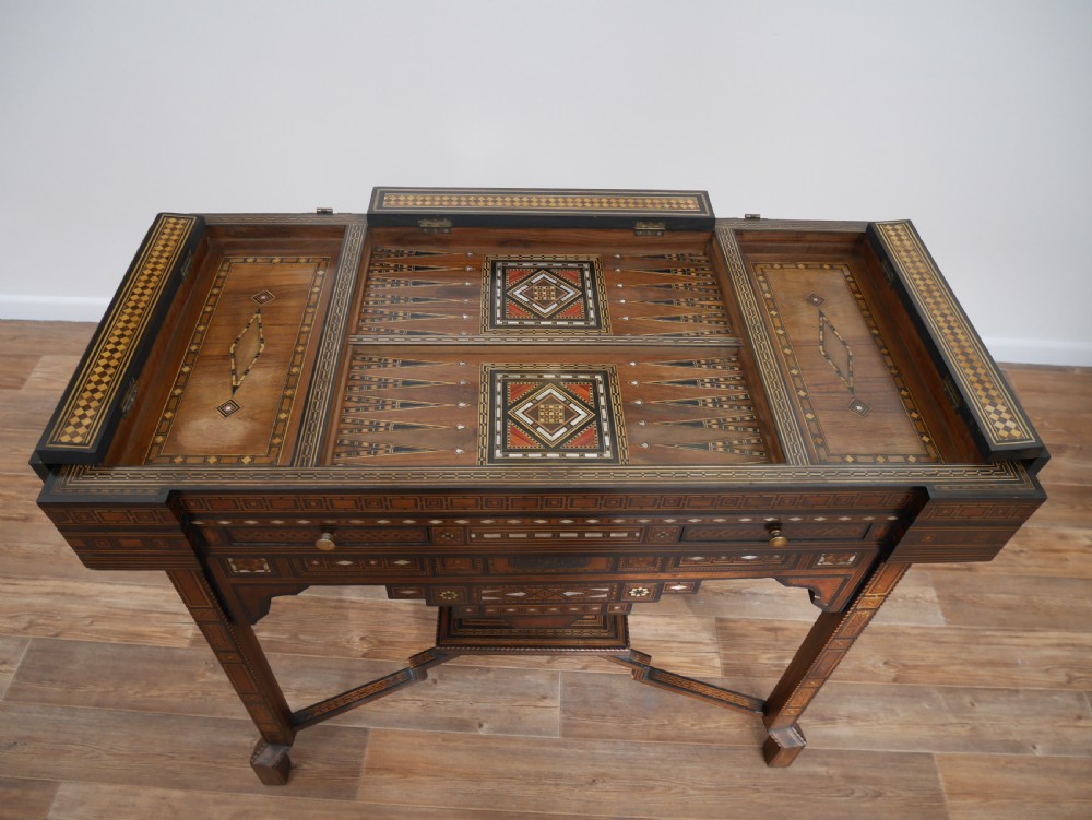 An antique rectangular Syrian games table featuring geometric micro-mosaic wood and mother-of-pearl inlays, turned drawers, and an intricate lower stretcher frame. View VII