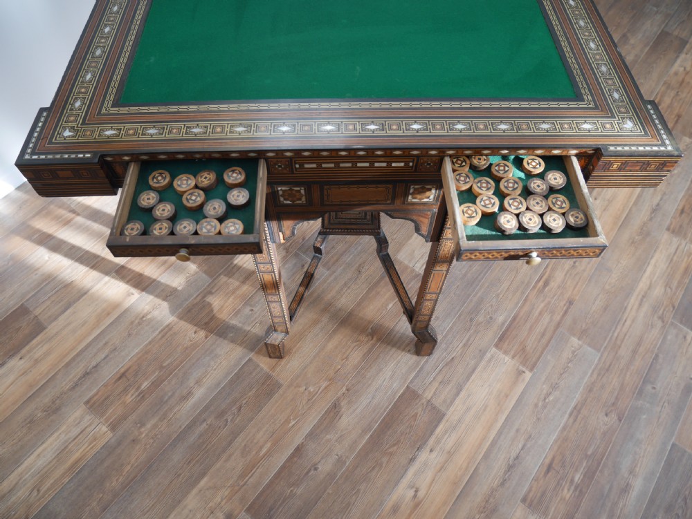 An antique rectangular Syrian games table featuring geometric micro-mosaic wood and mother-of-pearl inlays, turned drawers, and an intricate lower stretcher frame. View X