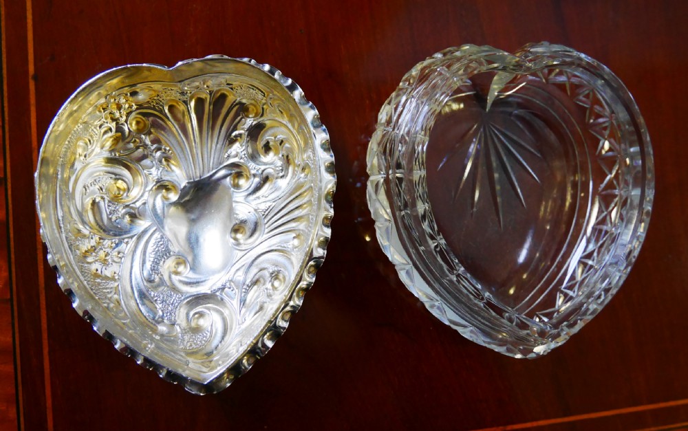 A heart-shaped cut glass trinket box featuring an embossed sterling silver lid decorated with scroll motifs. View II