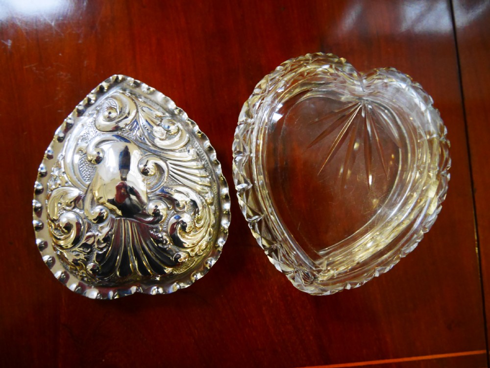 A heart-shaped cut glass trinket box featuring an embossed sterling silver lid decorated with scroll motifs. View III