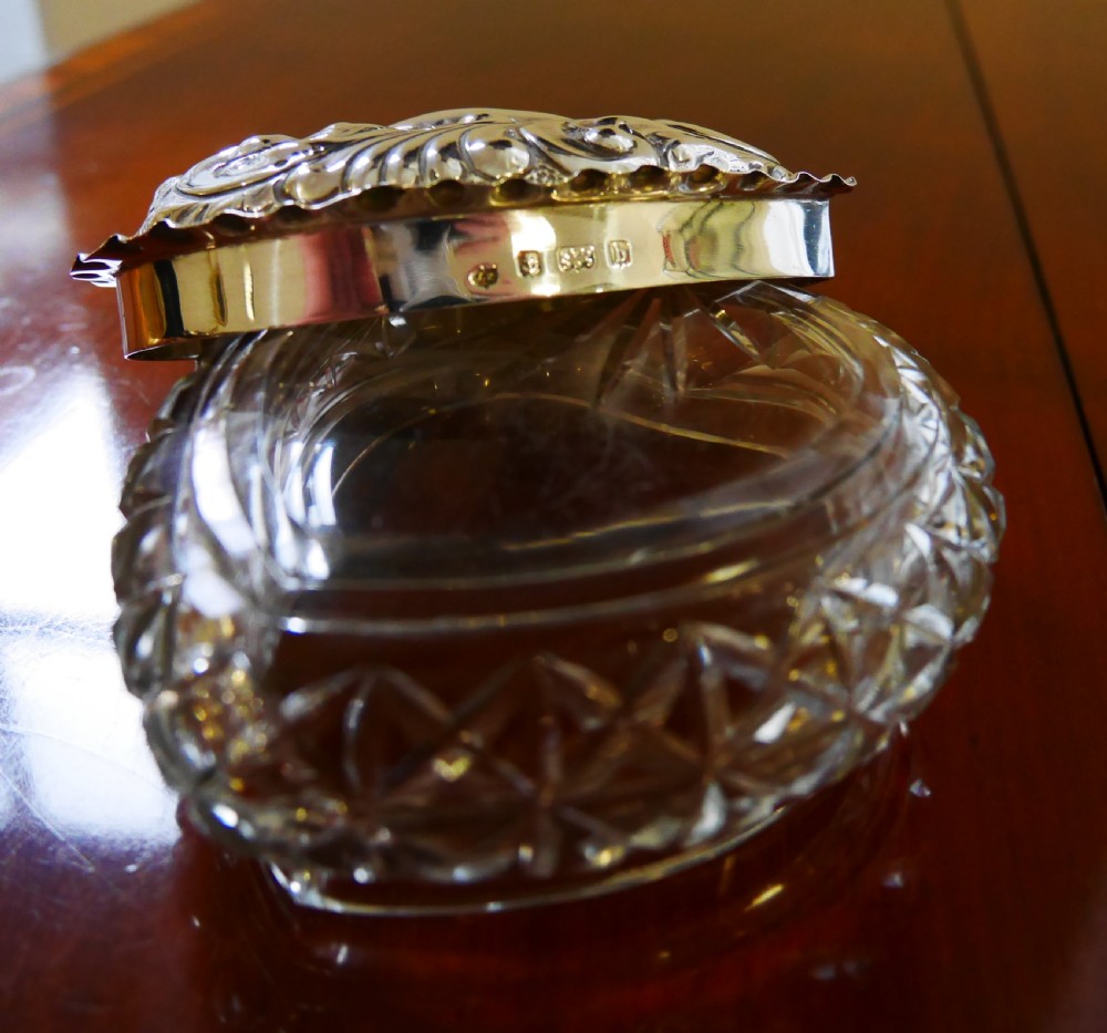 A heart-shaped cut glass trinket box featuring an embossed sterling silver lid decorated with scroll motifs. View IV