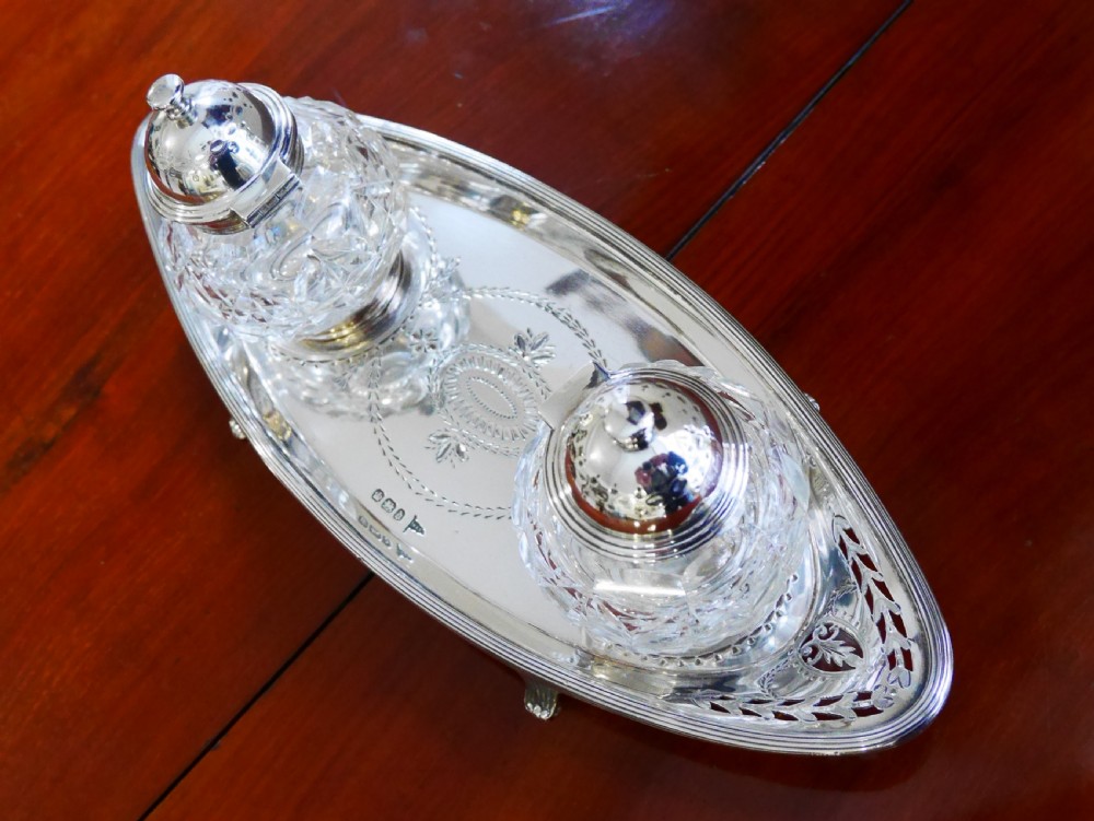A solid silver boat-shaped tray with pierced scrollwork edges and central engraving, holding two faceted cut-glass inkwells with silver caps. View II
