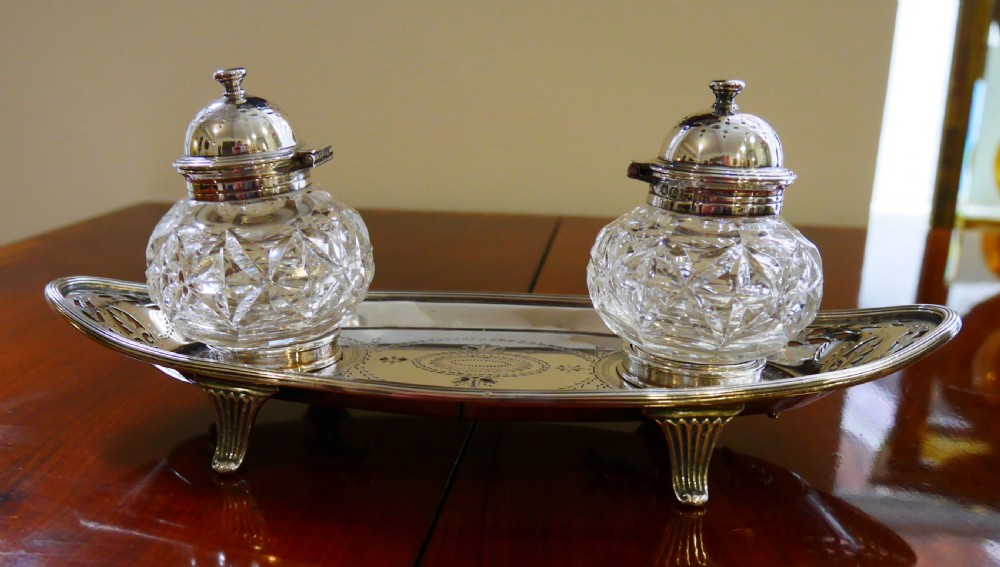 A solid silver boat-shaped tray with pierced scrollwork edges and central engraving, holding two faceted cut-glass inkwells with silver caps. View III