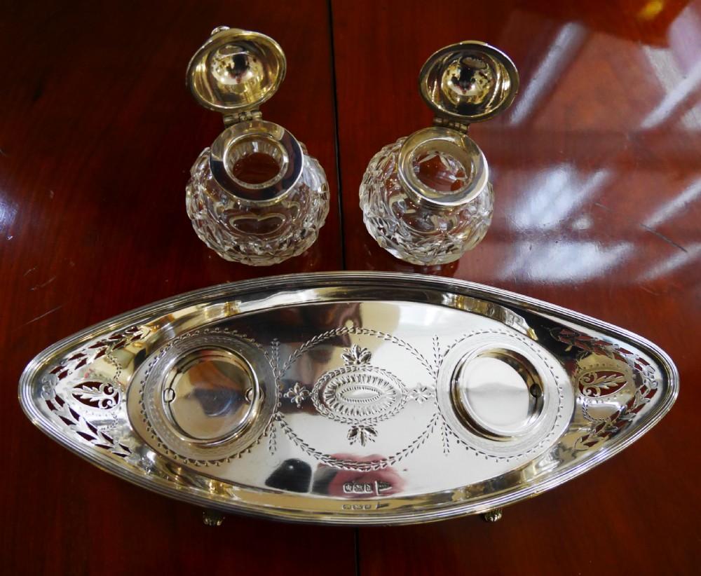 A solid silver boat-shaped tray with pierced scrollwork edges and central engraving, holding two faceted cut-glass inkwells with silver caps. View IV