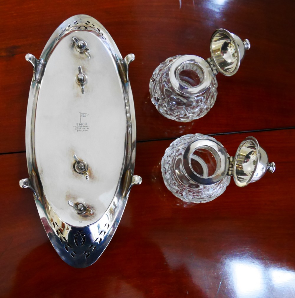 A solid silver boat-shaped tray with pierced scrollwork edges and central engraving, holding two faceted cut-glass inkwells with silver caps. View V