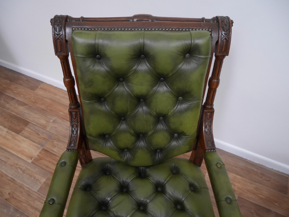 A pair of Victorian mahogany armchairs upholstered in deep-buttoned olive green leather with carved frames and brass castors. View IV