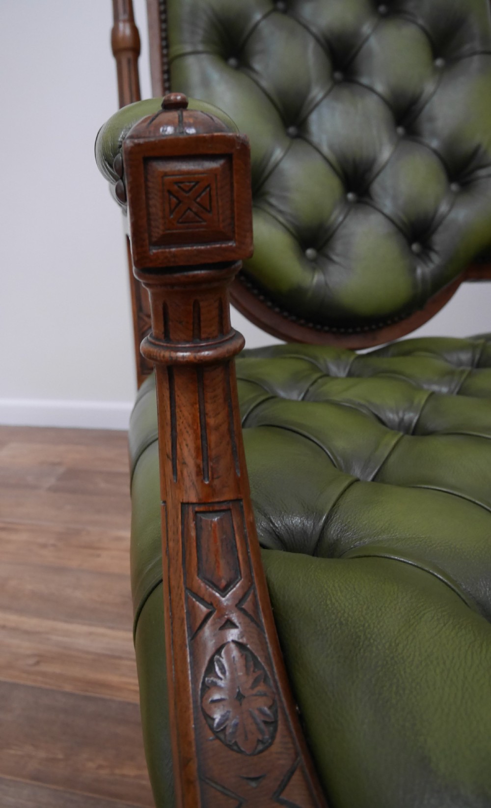 A pair of Victorian mahogany armchairs upholstered in deep-buttoned olive green leather with carved frames and brass castors. View VII