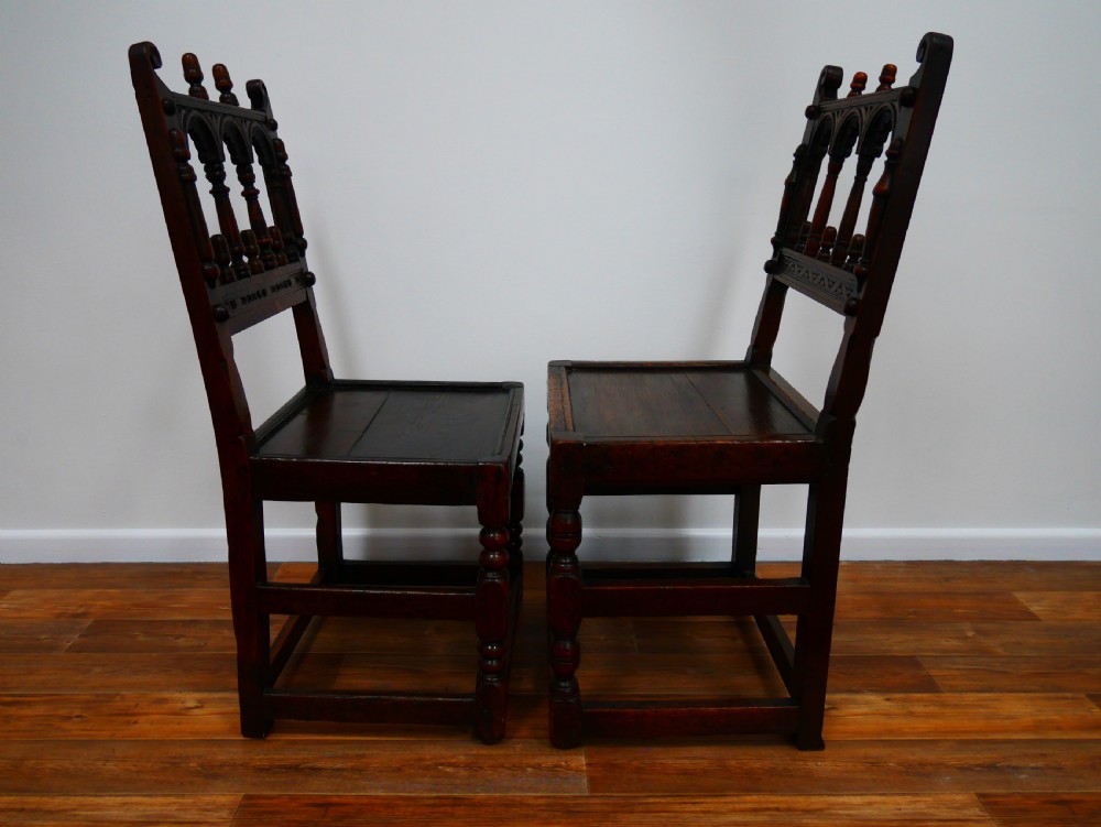 Pair of 17th-century dark oak Derbyshire side chairs featuring arcaded back rails with turned finials and solid wood panel seats. View IV