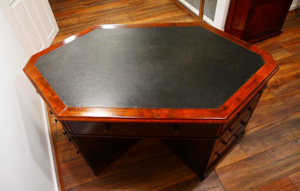 An octagonal Victorian mahogany pedestal desk with multiple drawers featuring turned wood handles and a dark inset leather writing surface. View II