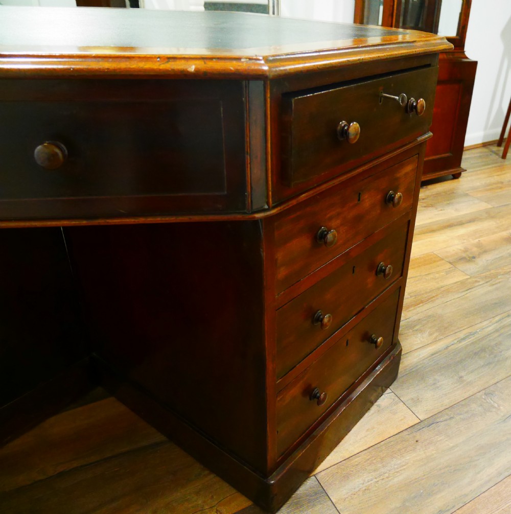 An octagonal Victorian mahogany pedestal desk with multiple drawers featuring turned wood handles and a dark inset leather writing surface. View III