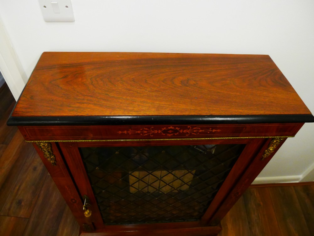 A nineteenth-century Victorian rosewood pier cabinet with a single glazed door, brass lattice detailing, floral marquetry inlay, and gilt brass mounts. View II
