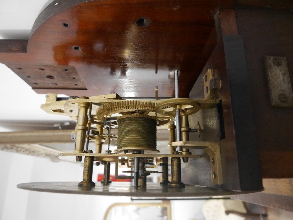 A Victorian mahogany regulator longcase clock featuring an arched hood, a circular white dial with Roman numerals, and a glazed trunk displaying the pendulum mechanism. View V
