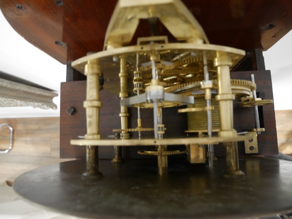 A Victorian mahogany regulator longcase clock featuring an arched hood, a circular white dial with Roman numerals, and a glazed trunk displaying the pendulum mechanism. View VII