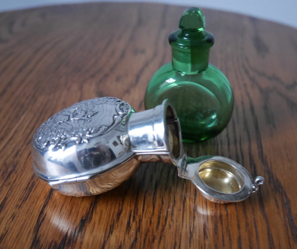 A circular Victorian sterling silver scent bottle decorated with a repousse pastoral scene and topped with a polished silver lid. View IV