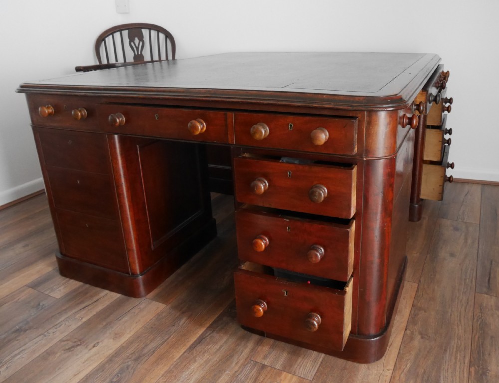 A 19th-century mahogany four-pedestal partners desk with a dark leather top, multiple drawers, and turned wooden knobs. View II