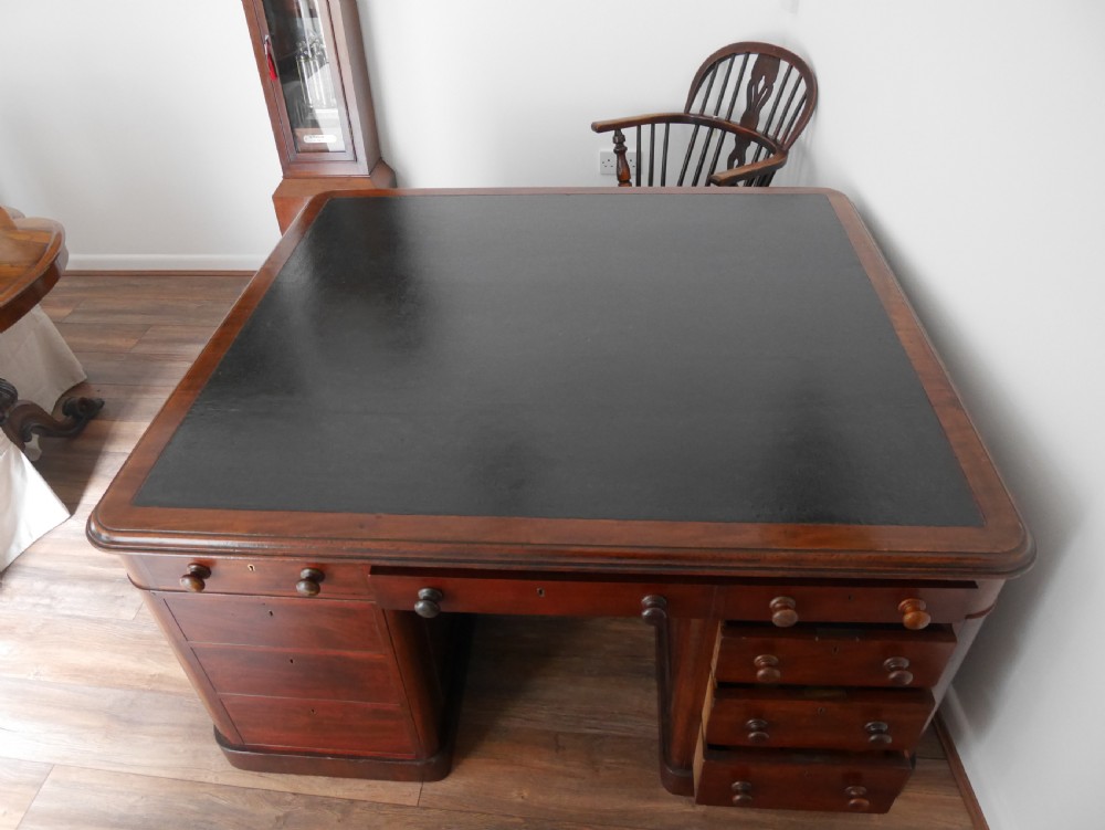 A 19th-century mahogany four-pedestal partners desk with a dark leather top, multiple drawers, and turned wooden knobs. View III