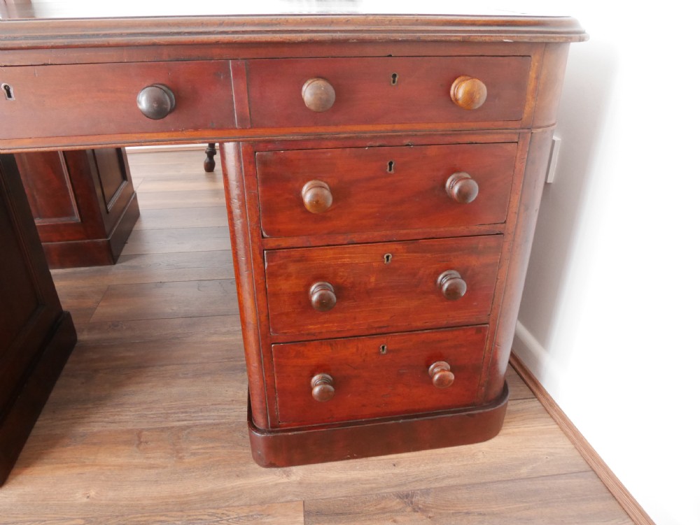 A 19th-century mahogany four-pedestal partners desk with a dark leather top, multiple drawers, and turned wooden knobs. View IV