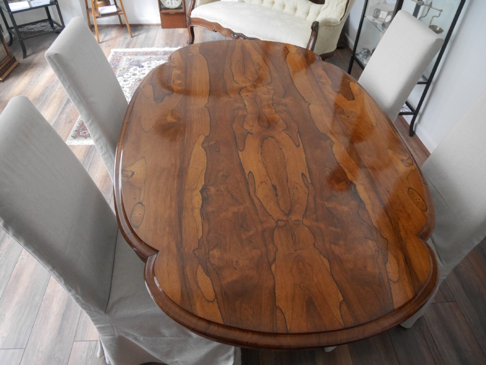 An antique Victorian rosewood centre table featuring a polished serpentine shaped top with prominent wood graining and carved scroll feet. View II