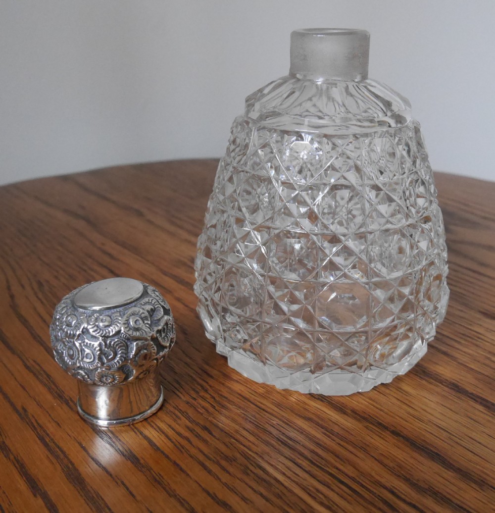 A clear cut-glass scent bottle with a diamond-patterned reservoir and an embossed, hallmarked sterling silver top. View II