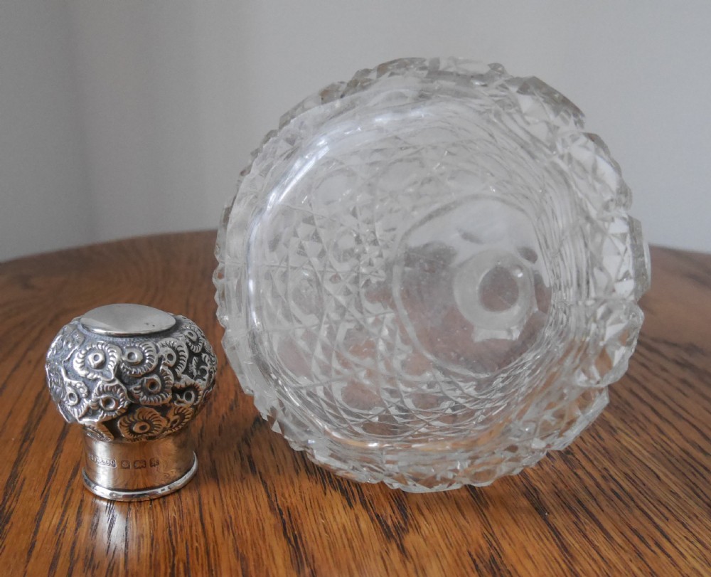 A clear cut-glass scent bottle with a diamond-patterned reservoir and an embossed, hallmarked sterling silver top. View III