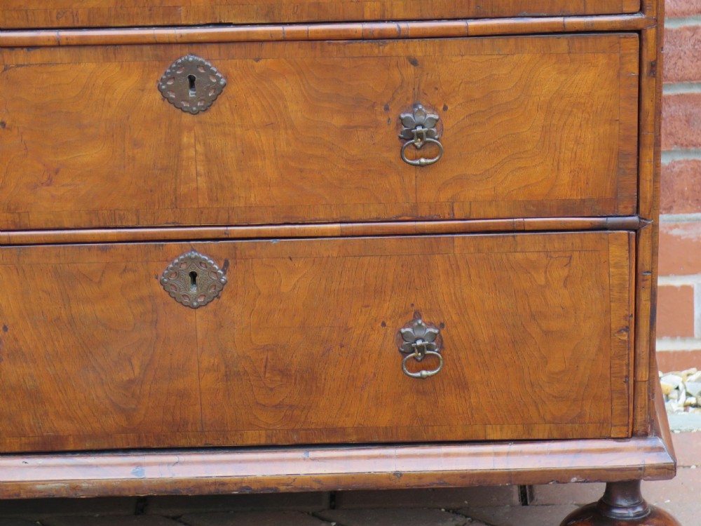 An early 18th-century Queen Anne period walnut chest of drawers featuring two short drawers over three long drawers, standing on turned bun feet. View VIII