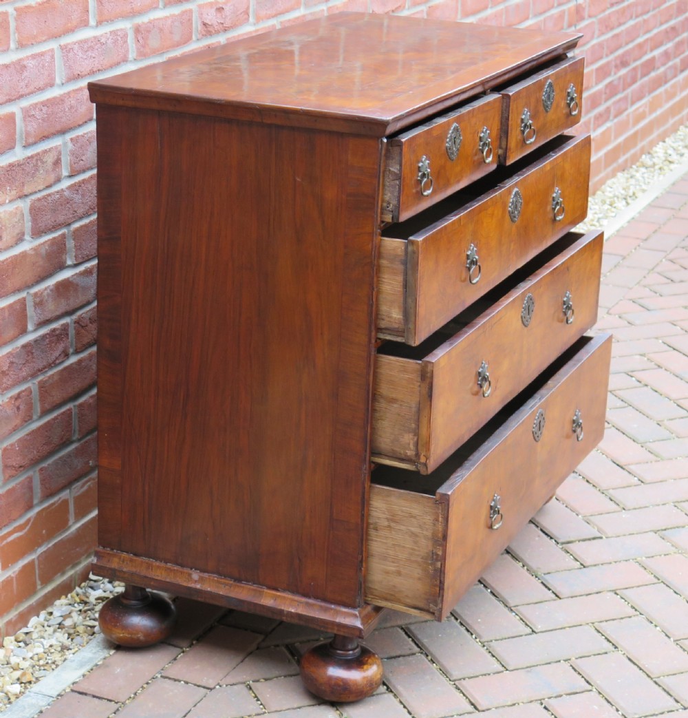 An early 18th-century Queen Anne period walnut chest of drawers featuring two short drawers over three long drawers, standing on turned bun feet. View XIII